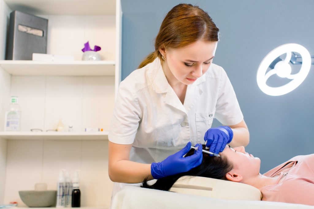 Procedure of hair mesotherapy. Young woman doctor cosmetologist makes the procedure of mesotherapy