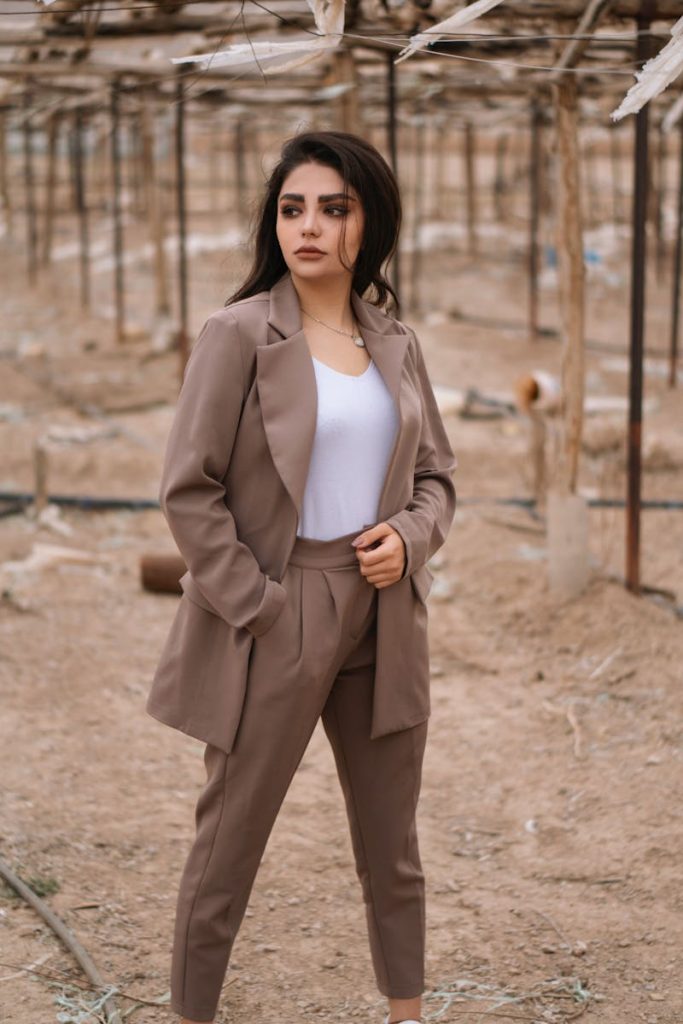 Confident woman in tan blazer posing outdoors with natural background.