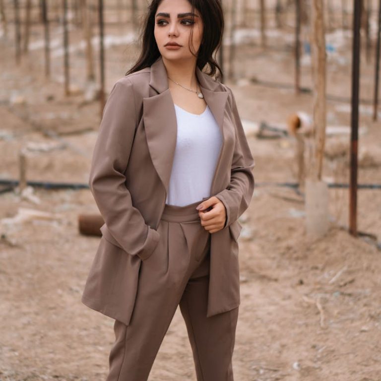 Confident woman in tan blazer posing outdoors with natural background.
