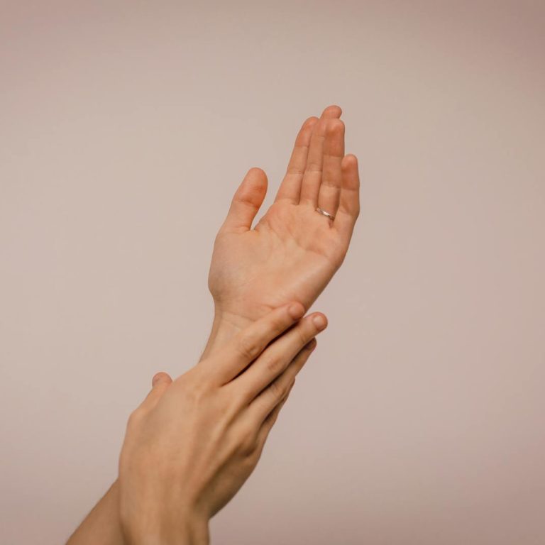 Close-up of hands gently caressing each other, symbolizing self-care and softness.
