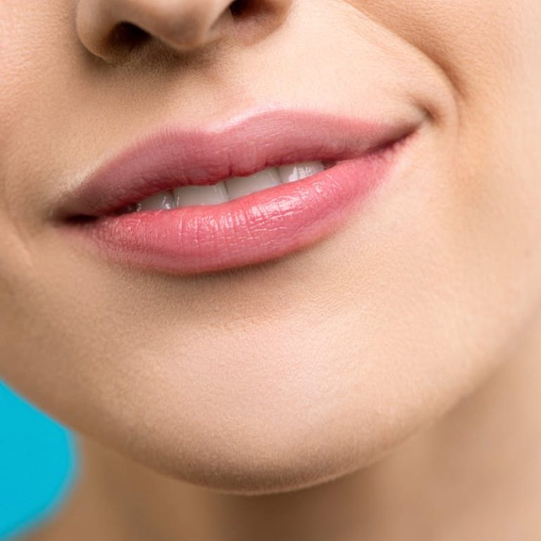 A detailed close-up shot of a woman's smiling lips showcasing smooth skin and lipstick.